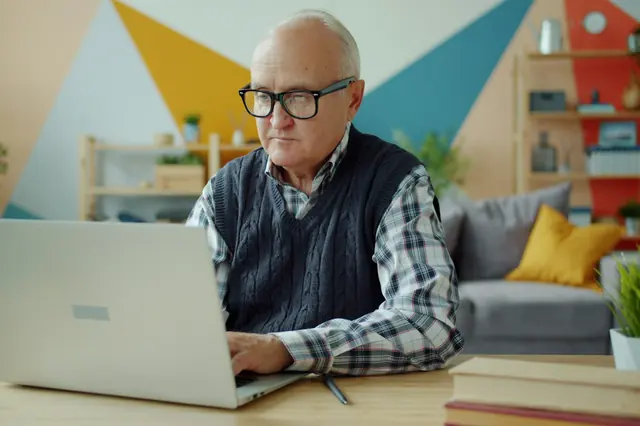 Älterer Mann arbeitet zu Hause konzentriert am Laptop