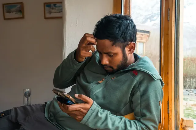 Mann schaut zu Hause nachdenklich auf sein Smartphone