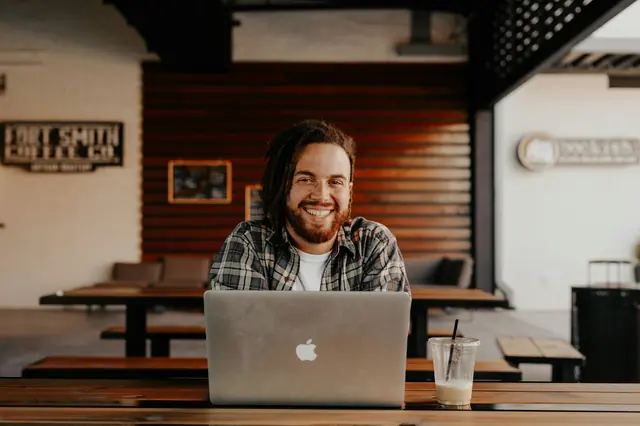 Lächelnder Mann mit Laptop in einem Café